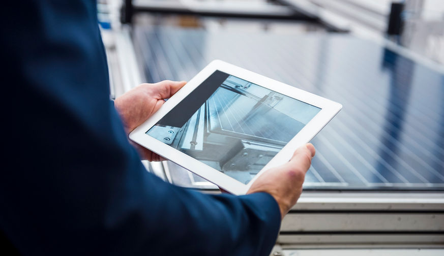 Person begutachtet Solaranlage auf einem Tablet